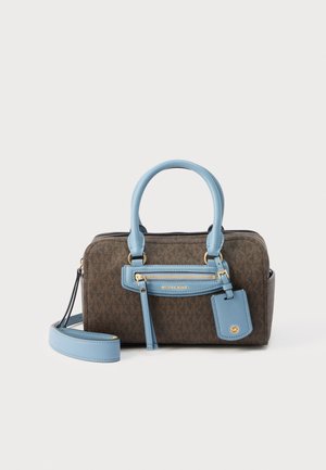 Καφέ τσάντα Michael Kors με μονόγραμμα, λαβές σε ουρανί χρώμα, μπροστινή τσέπη με φερμουάρ και αποσπώμενο λουρί ώμου σε λευκό φόντο.