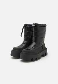 Melni pūkaini potītes zābaki ar gumijas zoli, ar vertikālu quilted tekstūru, regulējamu auklu un masīvu platformas dizainu.