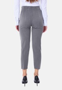 Pantaloni grigi su misura con una vestibilità slim e una vita strutturata, caratterizzati da cuciture verticali come dettaglio di design, abbinati a tacchi neri.