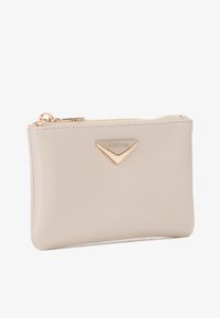 Pochette in pelle beige con zip dorata e accentuazione a logo triangolare, caratterizzata da una texture liscia e un design minimalista.