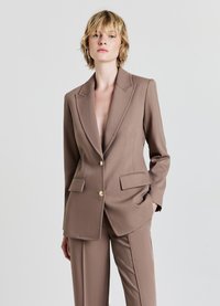 Blazer marrone su misura con rever, bottoni dorati e due tasche frontali. Il tessuto ha una texture liscia e un design strutturato.
