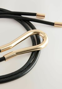 Corda in pelle nera con chiusura in metallo dorato. La chiusura presenta un design curvo, mentre la corda è texturizzata e liscia con dettagli di cucitura.