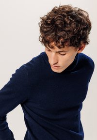 Dunkelblauer Strickrollkragenpullover mit weicher Textur, taillierter Passform und langen Ärmeln, mit einem glatten, ungemusterten Finish.