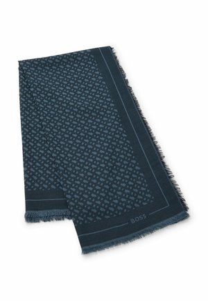Écharpe bleu foncé à motifs présentant un design géométrique, des bords effilochés et une bordure contrastante avec le nom de la marque affiché discrètement.
