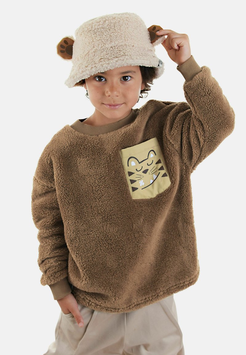 Sudadera de forro polar marrón con un bolsillo beige claro que presenta un gráfico de un tigre; combinada con un sombrero de cubo beige con orejas de oso.