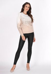 Beige és fehér degradé pulóver, flitter díszítéssel, fekete leggings-szel és nude magassarkú cipővel párosítva, kerek nyakkivágással és hosszú ujjakkal.