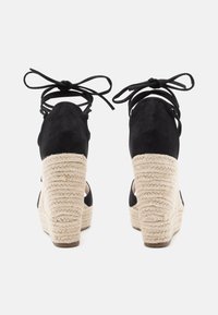 Schwarze Wildleder-ESPADRILLES mit einem gewebten Jute-Plateau. Mit Knöchelbindungen und offenen Seiten. Texturierte Oberfläche und robustes Design.
