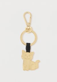 Kultainen metallinen kissamuotoinen avaimenperä mustalla hihnalla, kiinnitetty pyöreään avainrenkaaseen, jossa on klipsi turvallista kiinnitystä varten.