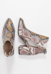 Botines de tobillo con punta abierta y diseño de piel de serpiente con estampado en tonos dorados, rosas y azules; cuentan con un tacón grueso y un detalle recortado en el lateral.