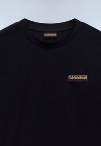Black cotton t-shirt with a round neck, featuring a small rectangular logo patch in contrasting colors on the left chest area.