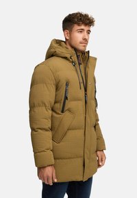 Polstret parka i olivengrøn, med en quiltet tekstur, justerbar hætte, frontlommer og sorte lynlåse med toggledrag.