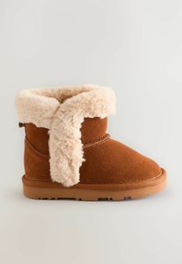 Brune ruskind ankelstøvle med en fluffy beige faux fur krave, stikninger og en gummisål med trækk mønster.