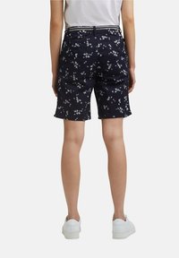 Námořnické šortky s květinovým vzorem, vybavené zajištěným pasem a kapsami. Materiál má hladkou strukturu; lemy jsou mírně roztrhané.