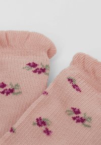 Lyserøde strikkede sokker med ribbet struktur, prydet med et blomsterdesign i lilla og grønne farver. Ribbenene har en blød, rullet finish.