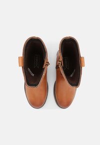 Bottines en cuir marron à finition lisse, fermeture éclair et boucle pour un enfilage facile. Intérieur doublé d'un tissu sombre.