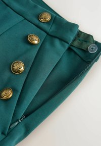 Teal kangas sileda tekstuuriga; sisaldab viit dekoratiivset kuldset nuppe, luku sulgemist ja voltimistetaili vööl.
