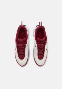 Balti ir bordo Nike sneakeriai su tekstūruotu viršumi, apvaliu pirštu, paminkštinta apykakle ir juodais logotipų akcentais. Įrengti su raištelių uždarymu ir kontrastingu padu.
