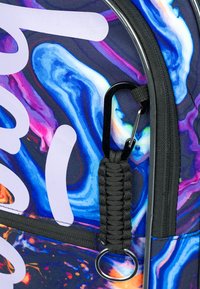 Zaino multicolore con un motivo vorticoso in blu, rosa e viola, completo di un moschettone nero e un cursore della cerniera texturizzato.