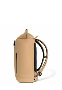 Mochila beige texturizada con parte superior redondeada, panel lateral negro y bolsillo frontal con cremallera. Cuenta con correas ajustables y detalle del logo en la base.
