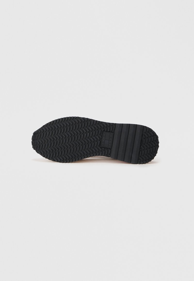 Black rubber shoe sole with a patterned texture, featuring deep treads and segmented sections for grip and stability.