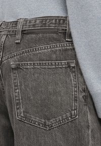 Γκρίζα τζιν παντελόνια με πίσω τσέπη, που διαθέτουν ραμμένο σχέδιο και μια μαύρη δερμάτινη ετικέτα στη ζώνη. Μαλακό υλικό με υφή.