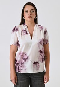 Blusa a maniche corte in seta bianca con motivo floreale viola, dotata di scollatura a V profonda e maniche leggermente a sbuffo. Tessuto morbido.