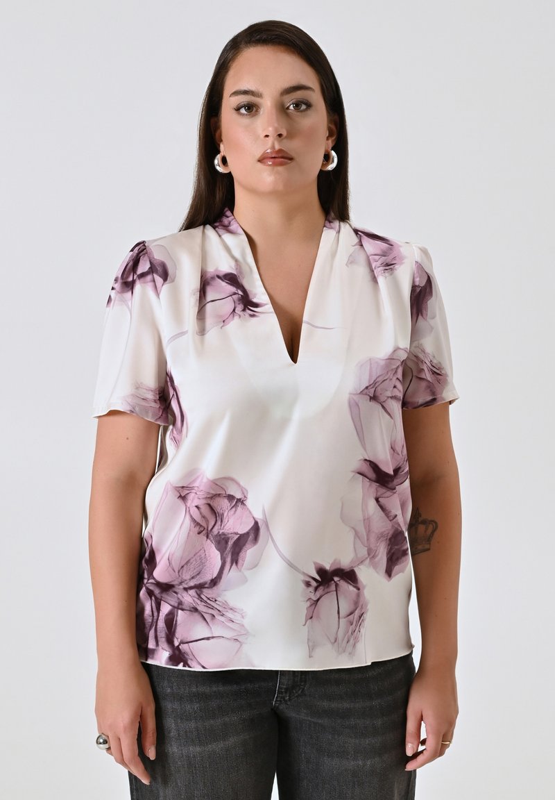 Blusa a maniche corte in seta bianca con motivo floreale viola, dotata di scollatura a V profonda e maniche leggermente a sbuffo. Tessuto morbido.