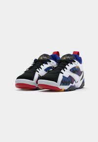 Un paio di sneaker basse con motivi zigzag neri, bianchi, blu, rossi e gialli, con linguette rosse su uno sfondo bianco.