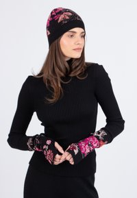 Schwarzer gerippter Rollkragenpullover mit langen Ärmeln, ausgestattet mit floralen Akzenten an den Bündchen. Strickstoff; taillierter Schnitt.