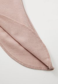 Helles rosa Gewebe, weiche Textur, gefaltete Kante mit sichtbarer Naht. Glatte Oberfläche, dreieckige Form, die die Nahtdetails hervorhebt.