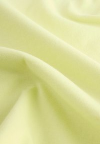 Plis de tissu doux de couleur jaune pastel clair montrant une texture fine tricotée et une surface lisse.