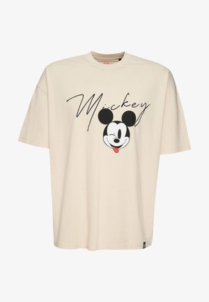T-shirt oversize beige in cotone, con una grande grafica di Topolino in bianco e nero con lingua rossa, e testo "Mickey" in corsivo.