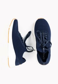 Scarpe sportive blu navy con tomaia in maglia, punta rotonda e suola in gomma bianca con grip testurizzato. Lacci lunghi e senza loghi visibili.