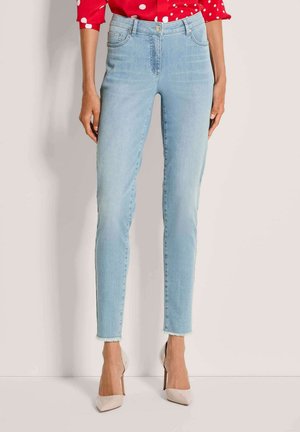 Lichtblauwe denim skinny jeans met een hoge taille, vijfzakkenontwerp en een rafelige zoom, gecombineerd met beige hoge hakken.