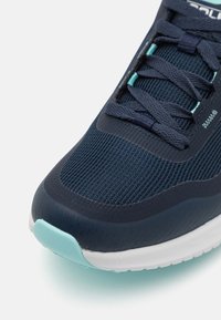 Granatowe buty sportowe z siateczkowej cholewki, teksturowanymi akcentami, turkusowymi detalami i białą gumową podeszwą. Posiadają sznurowany design.