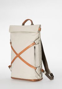 Beiger rechteckiger Rucksack mit braunen Lederriemen, die vorne ein X bilden, Tragegriff oben, seitliche Reißverschlusstasche und gepolsterte Schultergurte.