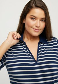 Das marineblaue und graue gestreifte Poloshirt hat einen V-Ausschnitt und einen Kragen. Der Stoff wirkt glatt und dehnbar, ideal für legere Anlässe.
