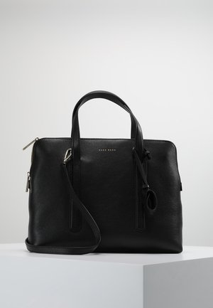 Zwarte leren handtas met dubbele handvatten en een afneembare schouderriem, geplaatst op een wit voetstuk tegen een effen achtergrond.