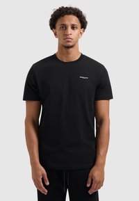 Zwarte korte mouwen t-shirt van katoen, met een ronde hals en een klein wit "BALLIN'" logo op de linkerborst.