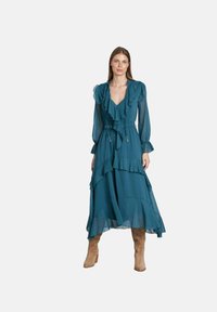 Türauftrag: Teal-farbenes, gestuftes Kleid mit Rüschensäumen und V-Ausschnitt. Hergestellt aus leichtem Stoff; verfügt über eine verstellbare Kordelzug-Taille und einen fließenden Schnitt.
