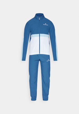 Blå treningsdrakt med jakke med glidelås og hvit horisontal stripe samt matchende bukser. Laget av et lett stoff med elastiske mansjetter.