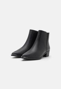 Pair of black leather ankle boots with pointed toes, low block heels, and elastic side panels on a white background.