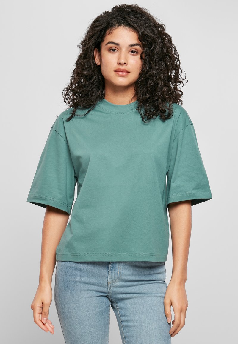 Türkisest värvist, lühikeste varrukatega t-särk, valmistatud pehmest puuvillast, sirge lõike ja ümmarguse kaelusega, kooshele hele siniste teksadega.