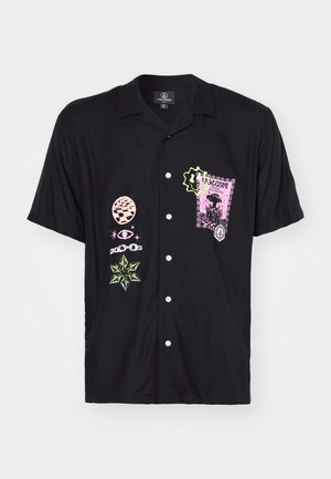 Chemise noire à manches courtes avec des imprimés graphiques de différentes couleurs, y compris un design de tampon rose et des accents verts, dotée d'un bouton sur le devant.
