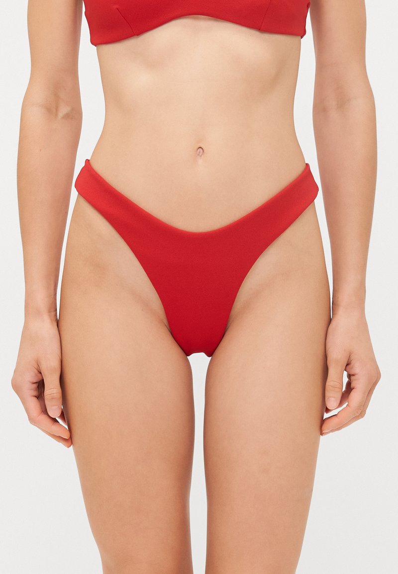 Červené bikini spodky s vysokým rezom na nohách, širokým pásom a hladkou matnou textúrou. Žiadne viditeľné vzory ani kovové detaily.