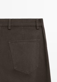 Pantaloni in denim marrone scuro con una vita semplice e una tasca posteriore. Il tessuto ha una trama caratteristica e linee pulite.