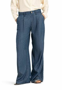 Lichte donkerblauwe denim broek met een losse pasvorm, geplooide voorkant en zijzakken. De zoom is lichtjes uitlopend en onafgewerkt.