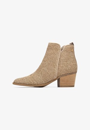 Stivaletto beige alla caviglia con texture intrecciata, punta a punta e tacco impilato. Presenta accenti chiari e una silhouette elegante.