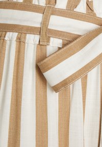 Ceinture rayée présentant des couleurs alternées beige et blanc, avec un tissu en lin texturé et un détail froncé à la taille pour un ajustement cintré.