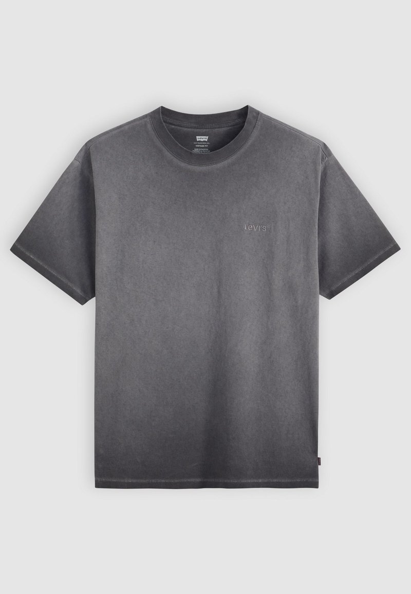 T-shirt en coton gris avec un col rond, des manches courtes et un logo discret sur la poitrine. Texture douce et coupe décontractée.